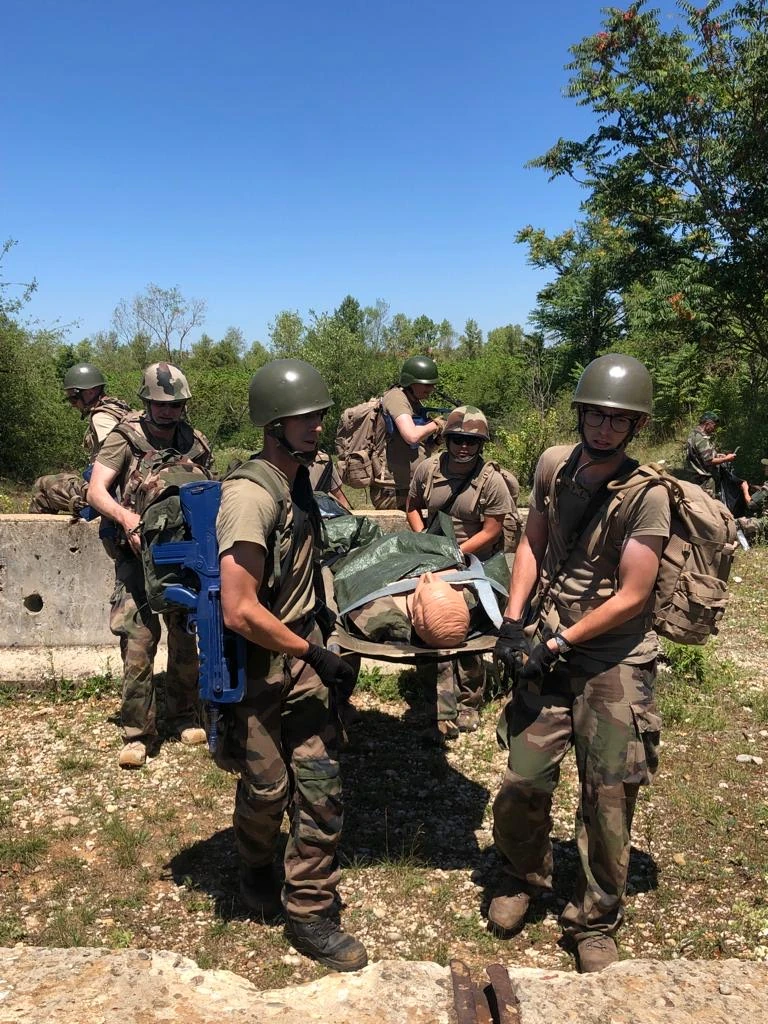 Un groupe de militaires transporte sur un brancard un mannequin d’entraînement en extérieur